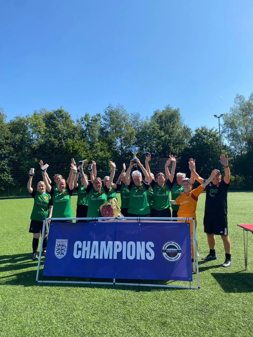 Bolton Town WanderHERS celebrating with the Lancashire Women’s Walking Football League champions banner