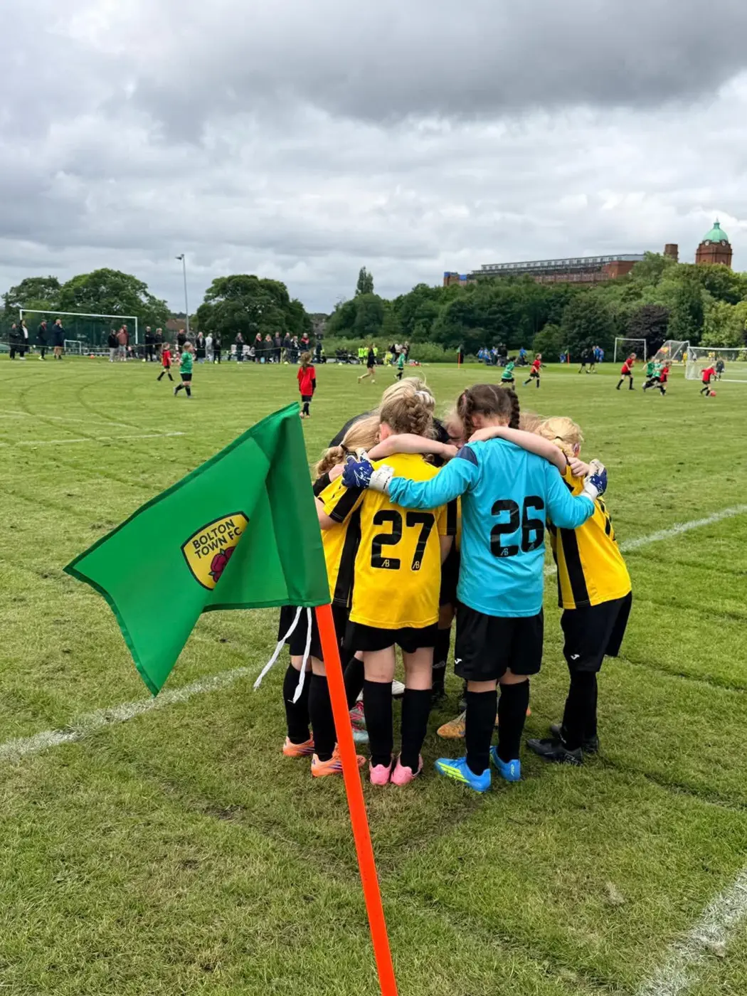 Bolton Town girls joining together in a team huddle