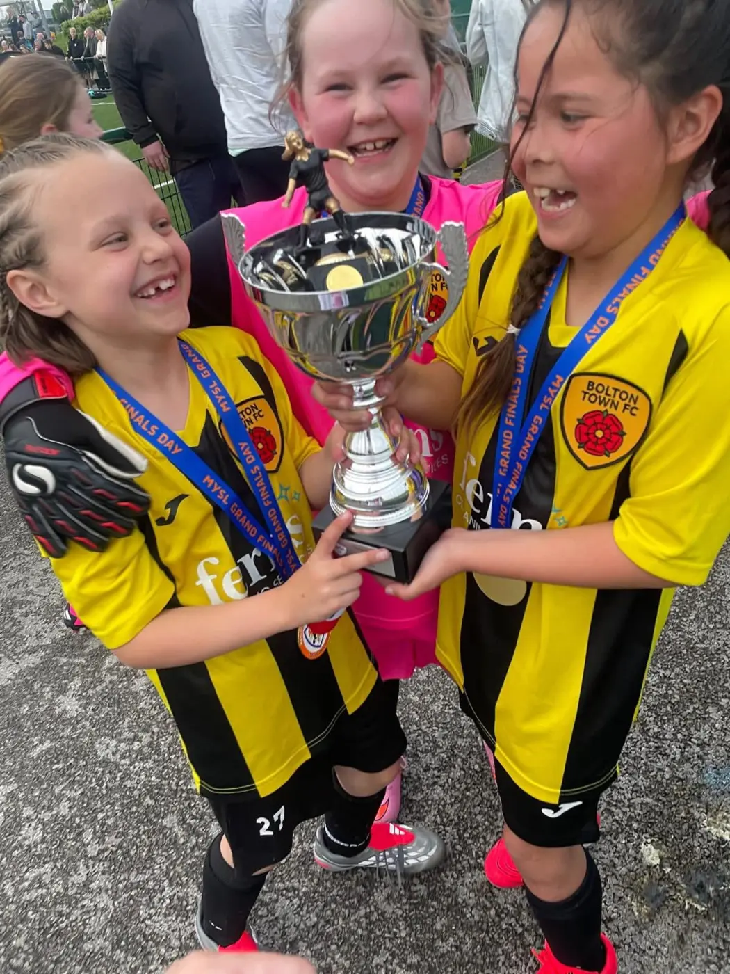 Three Bolton Town players celebrating together with a trophy