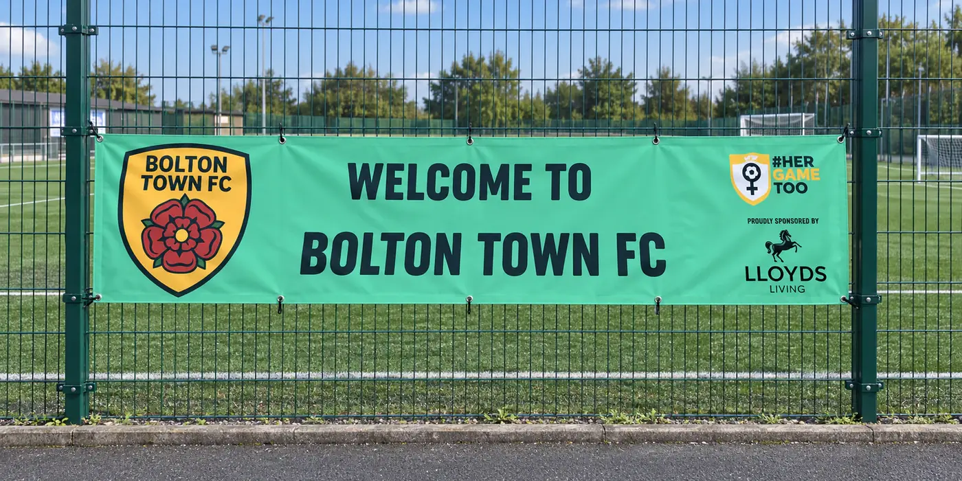 Bolton Town FC welcome banner hung on a green metal fence
